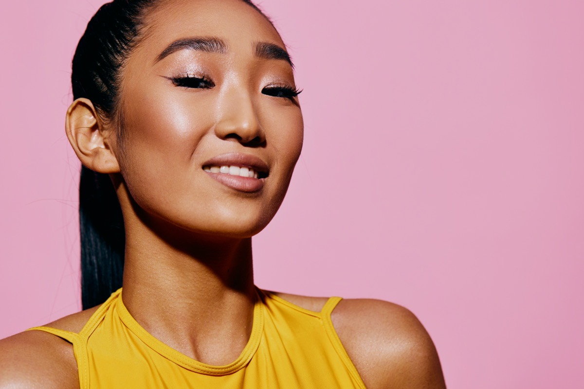 Woman with a glazed, dewy glow on pink